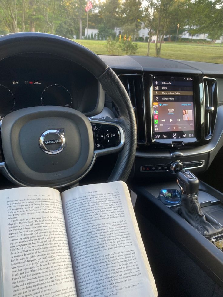 the interior of a car with an open book on the steering wheel and electronic display