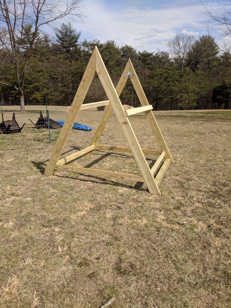 a wooden structure sitting on top of a grass covered field