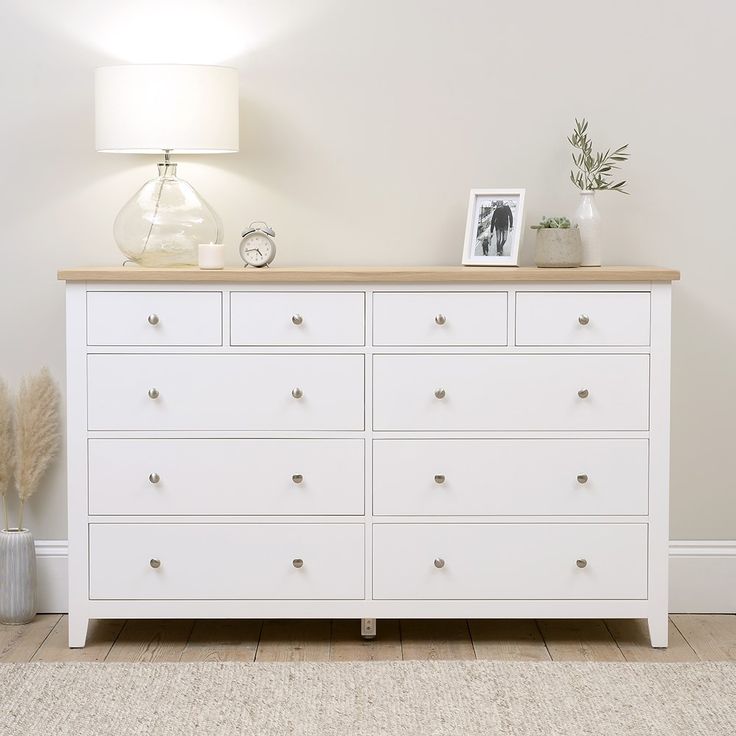 a white dresser with drawers and pictures on top