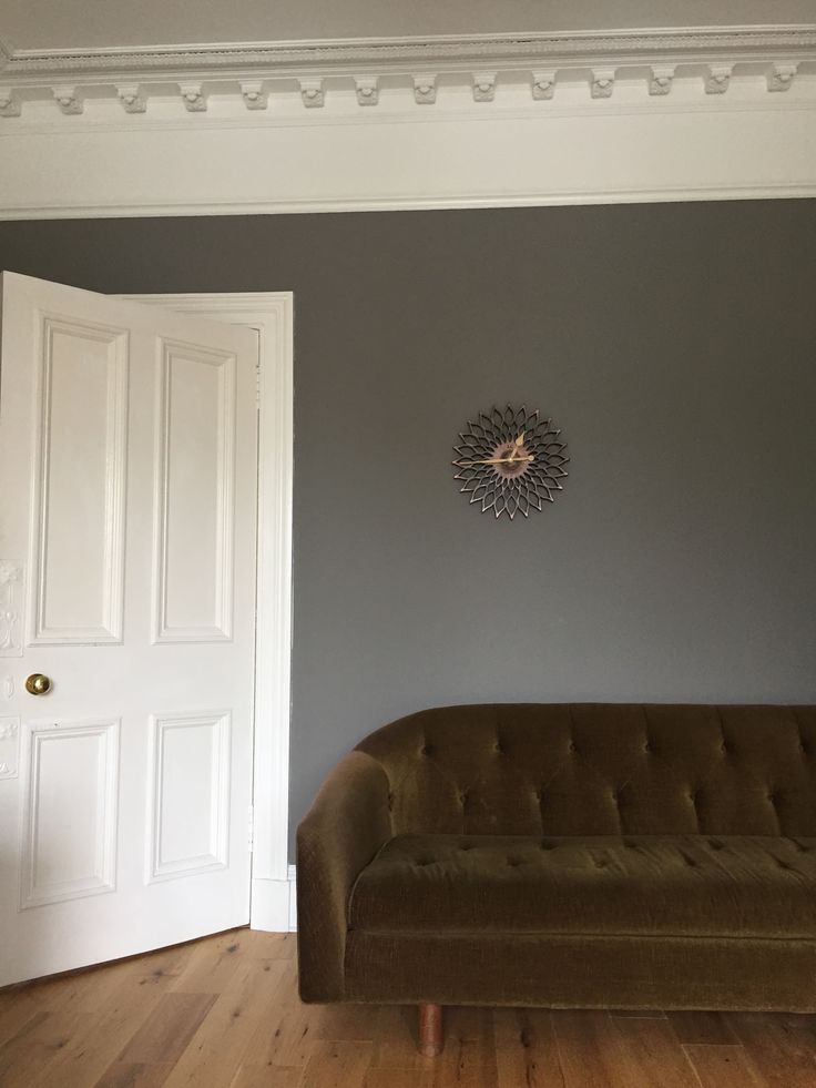 a living room with a brown couch and white door in the corner on the wall