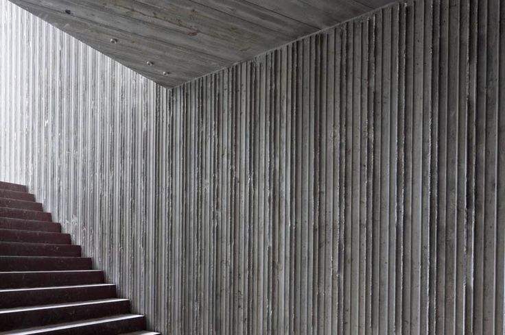 the stairs are lined with metal slats and there is a quote on it that reads, detail of the exposed concrete walls and wood that leads to