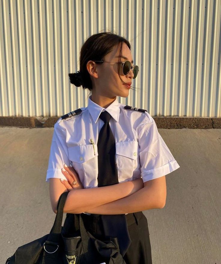 a woman in uniform is standing with her arms crossed and looking at the camera while wearing sunglasses