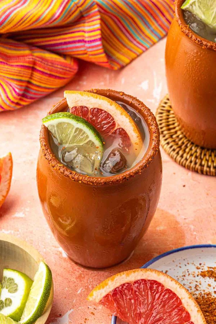 two glasses filled with blood orange margaritas and garnished with lime wedges