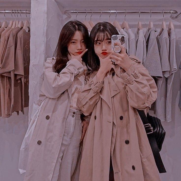 two young women taking a selfie in front of a rack of shirts and jackets