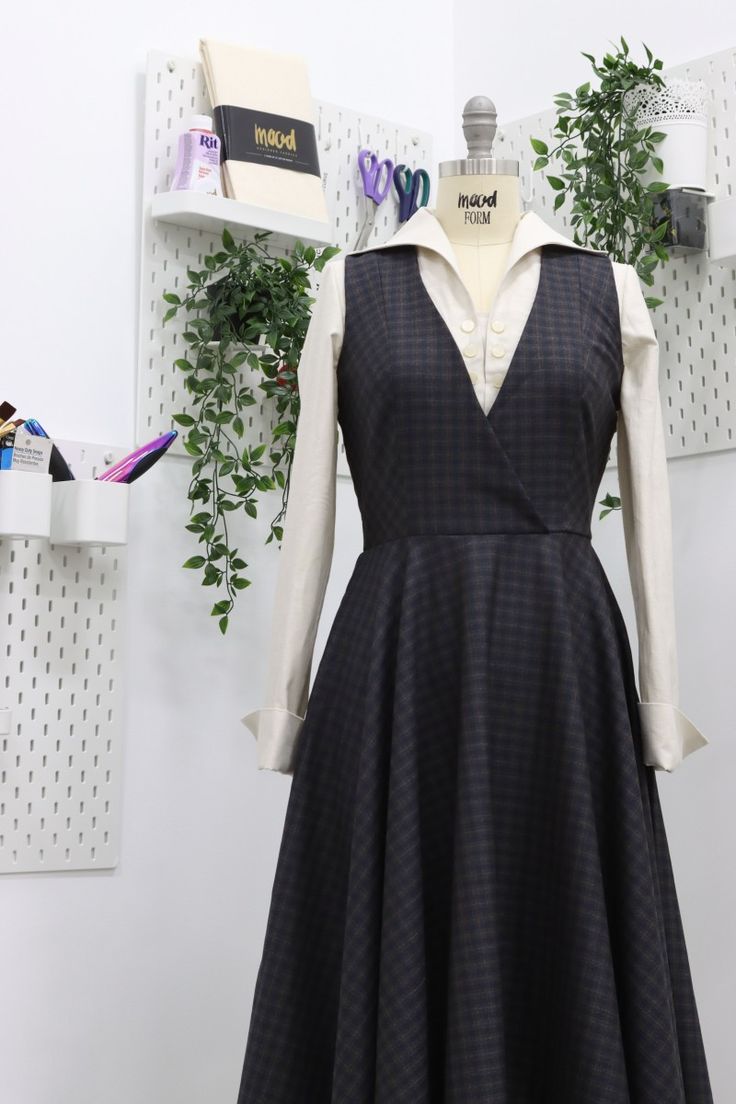 a dress is displayed on a mannequin in front of a wall with plants