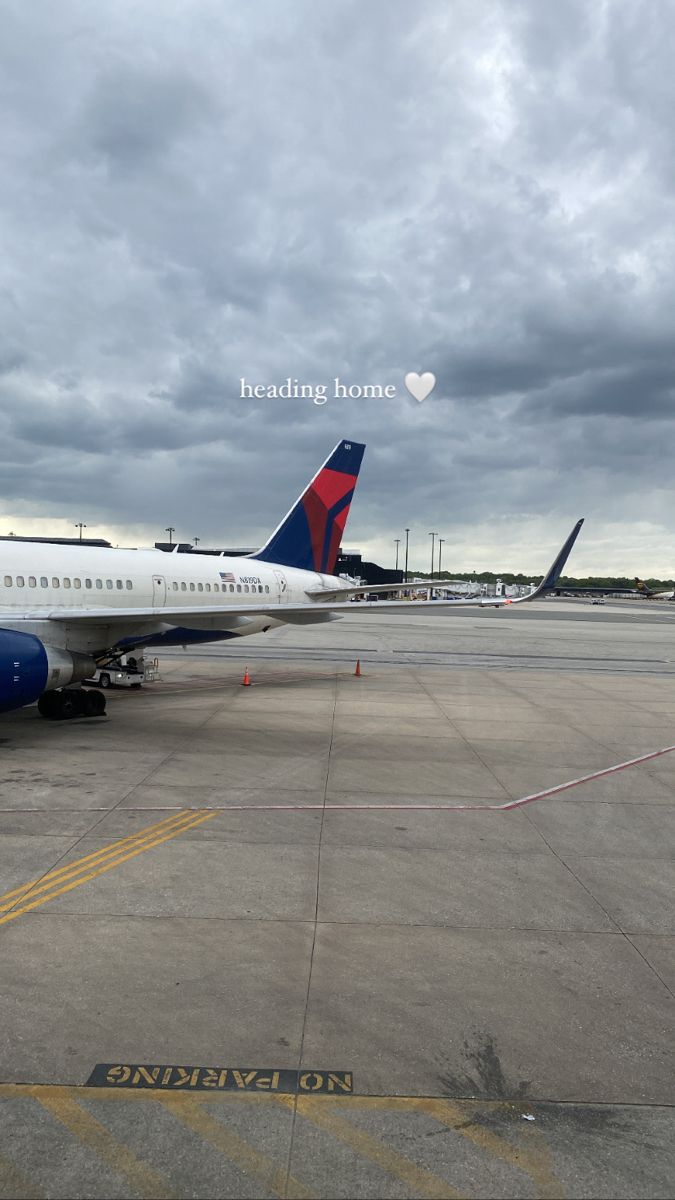 an airplane is parked on the tarmac under cloudy skies