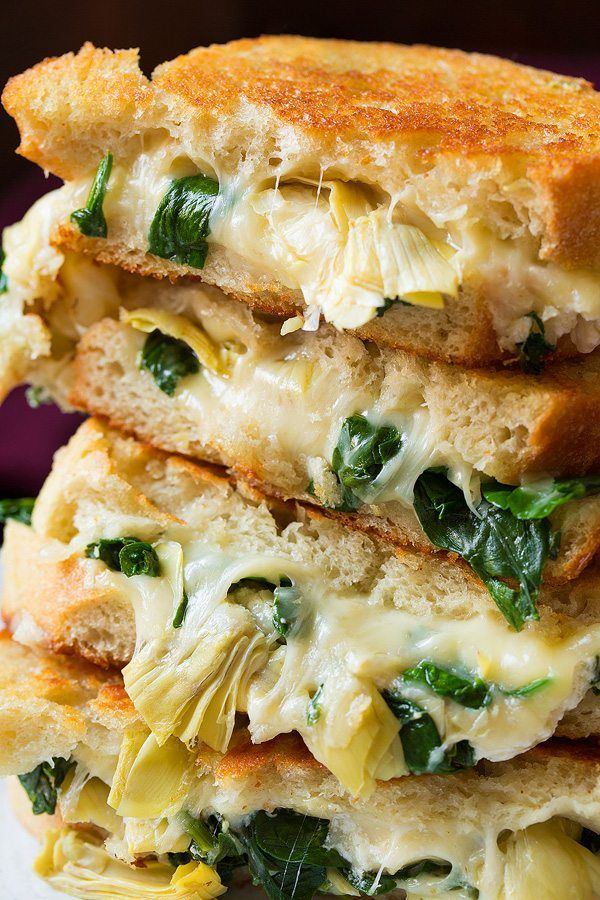 two grilled sandwiches stacked on top of each other with cheese, spinach and melted cheese