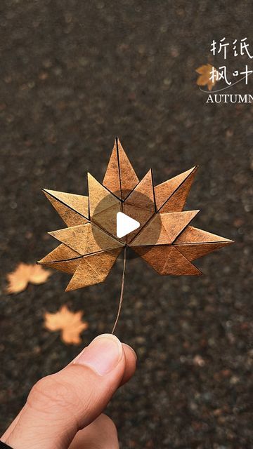 a person is holding an origami maple leaf in their hand, with the words autumn written on it