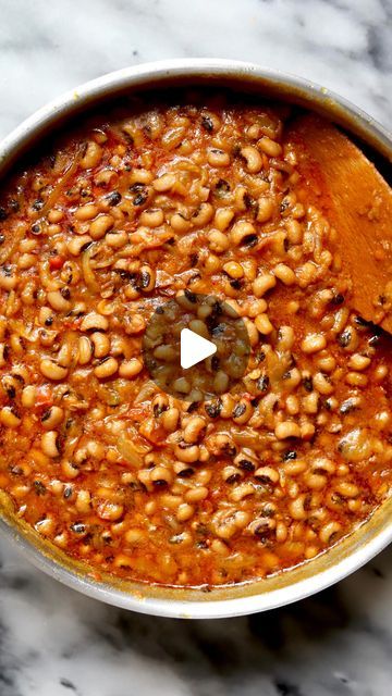 a pot filled with beans and sauce on top of a marble counter