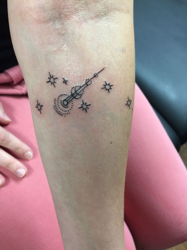 a woman with a tattoo on her leg that has stars and a rocket ship flying through the sky