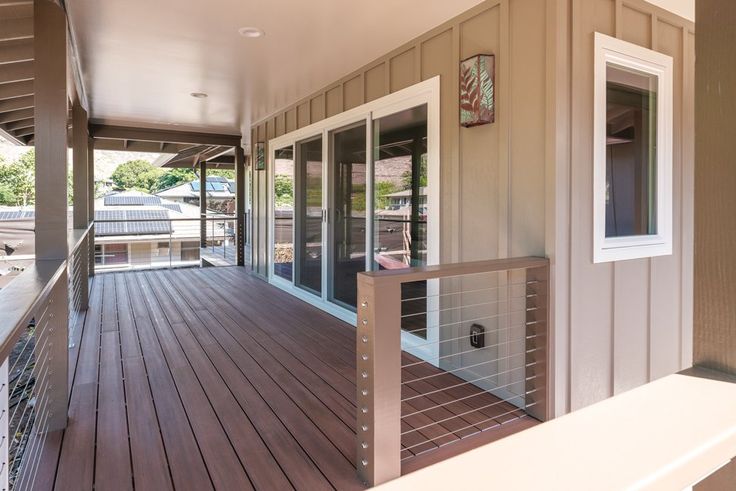 a balcony with wooden flooring and railings on the side of a house that has glass doors