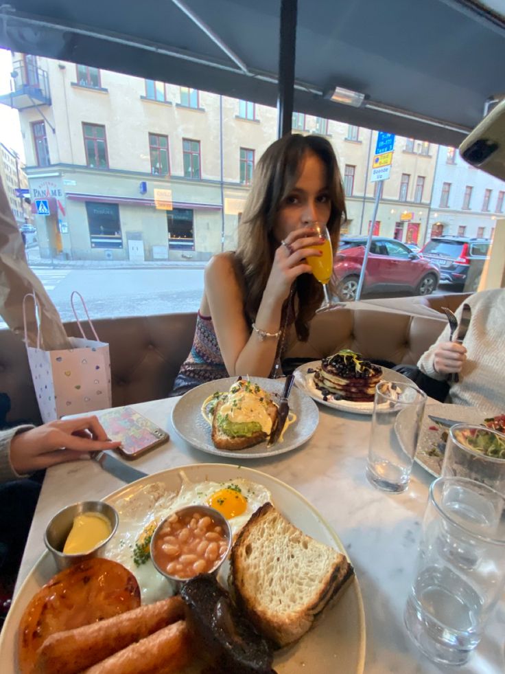 a woman sitting at a table with food and drinks