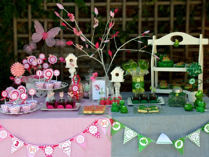 a table topped with lots of desserts and cupcakes next to a tree