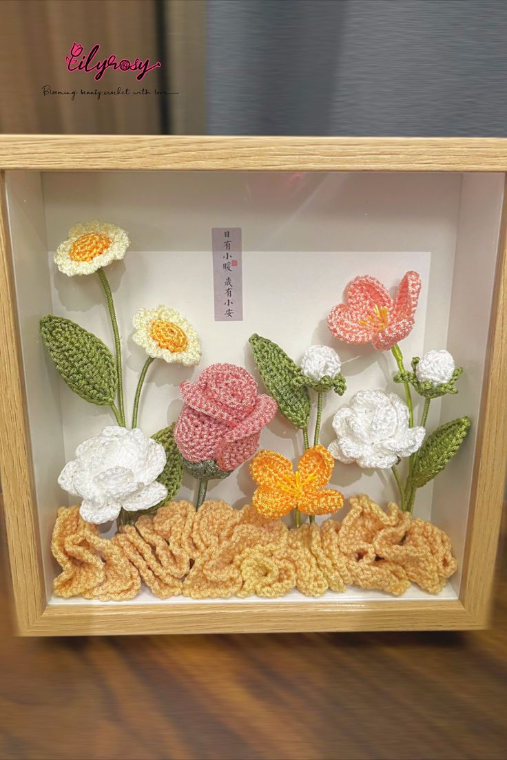 there are crocheted flowers in a shadow box