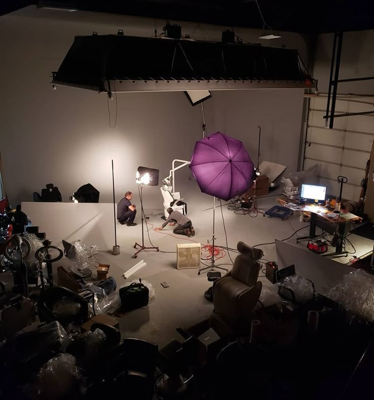 a photo studio with an umbrella and several lights on the floor in front of it