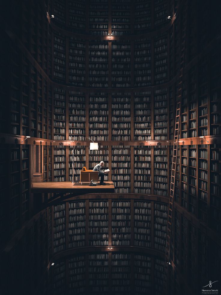 a room filled with lots of books next to a lamp on top of a table