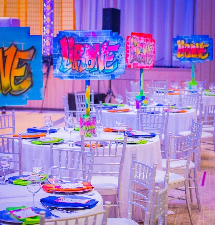 a room filled with lots of white tables covered in colorful plates and place settings for people to eat