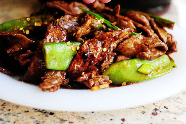 a plate full of food with meat and cucumbers on it, sitting on a table