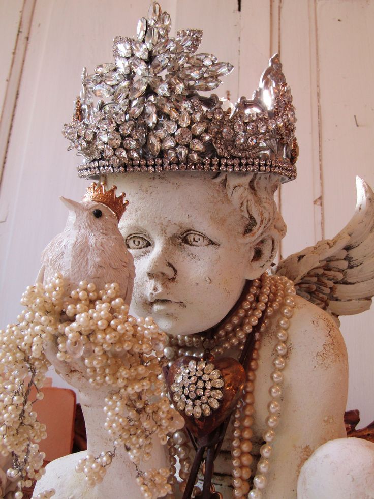 a white statue with pearls and a bird on it's head