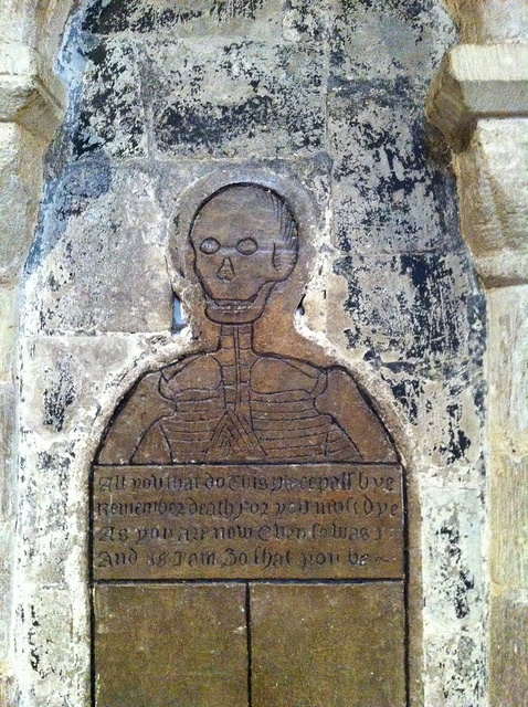 a stone wall with a carving of a skeleton on it