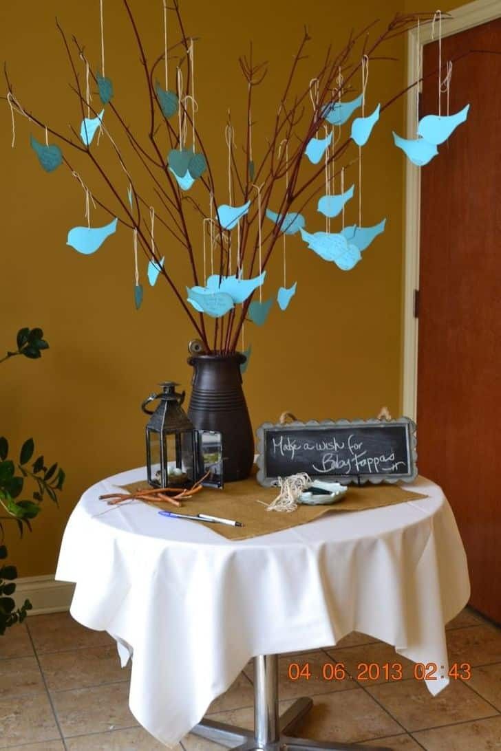 a table topped with blue paper birds next to a vase filled with flowers and branches