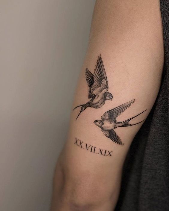 two birds with roman numerals tattoo on arm