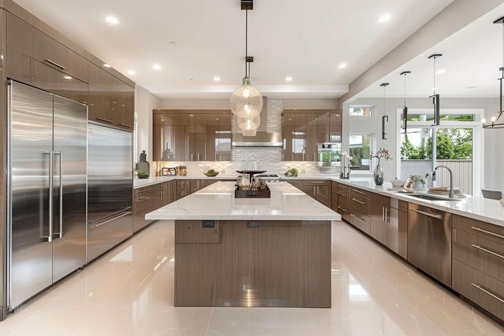 a large kitchen with stainless steel appliances and marble counter tops, along with an island in the middle