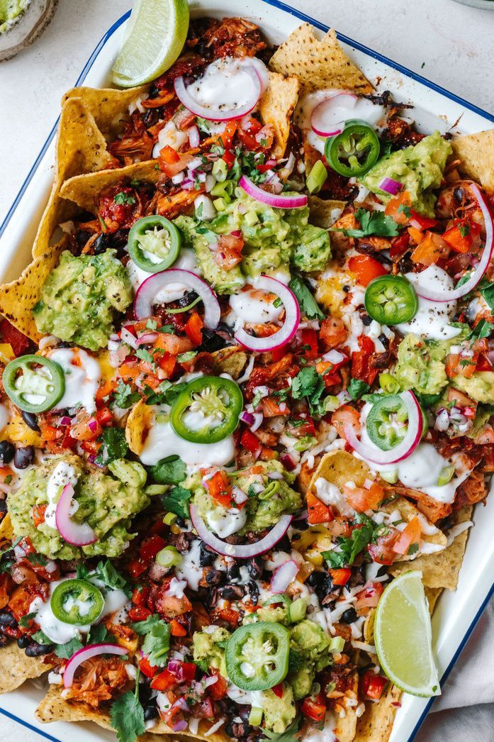 a platter filled with nachos topped with guacamole and onions