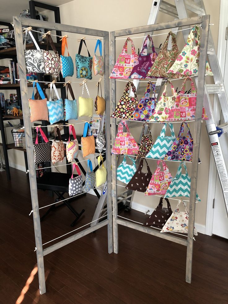 two shelving racks filled with purses on top of a wooden floor next to a ladder