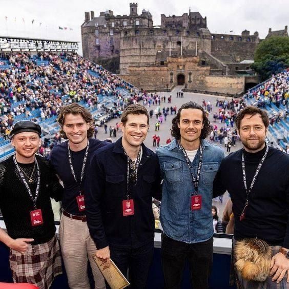 four men are posing for a photo in front of an audience at a sporting event