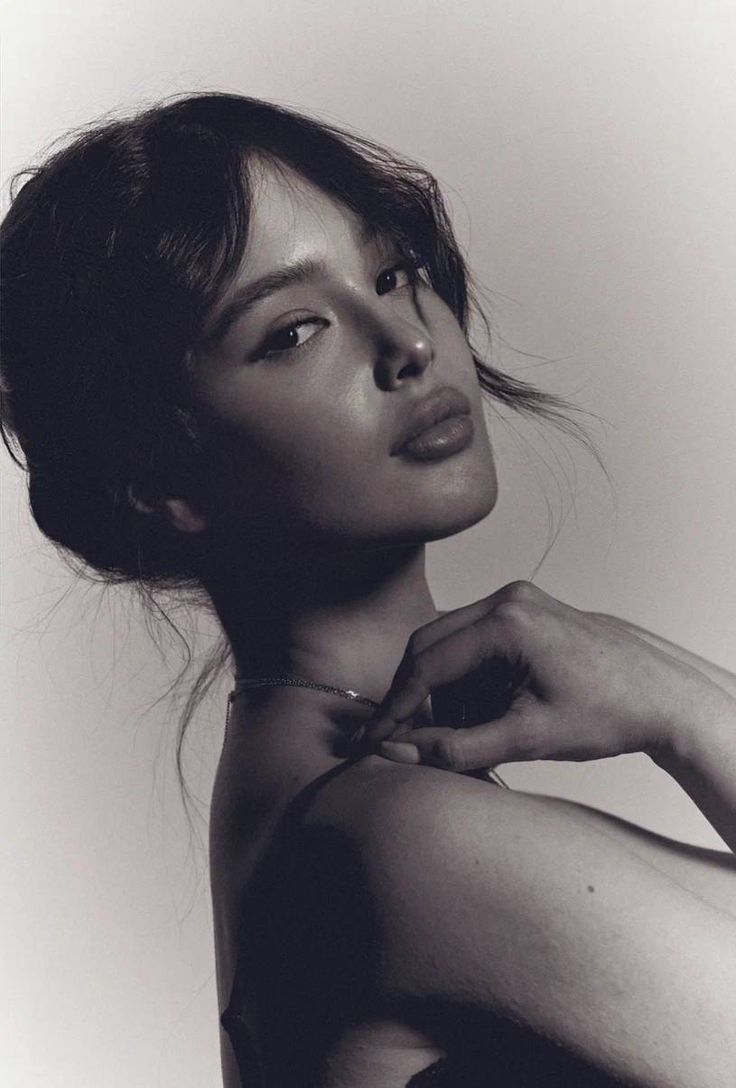 a black and white photo of a woman with her hands on her chest, looking off to the side