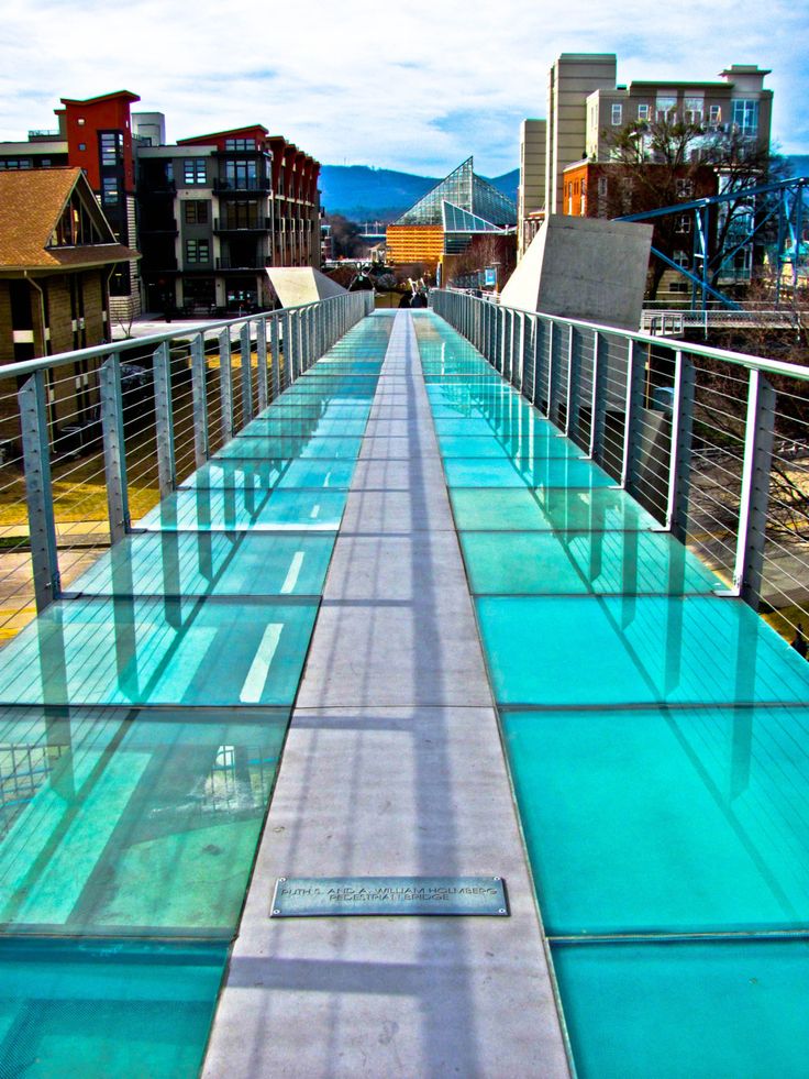 a long glass walkway with buildings in the background