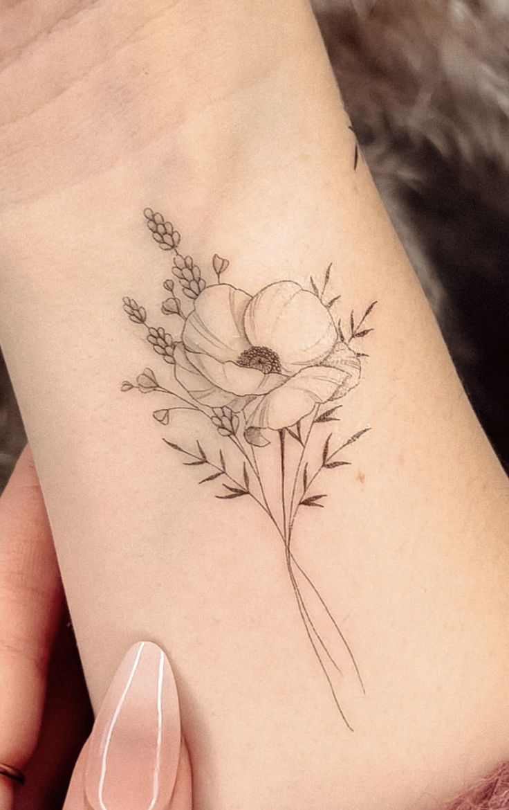 a woman's arm with a flower tattoo on the left side of her wrist