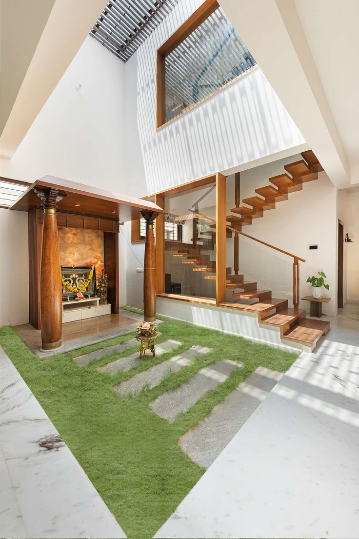 the inside of a modern house with grass in the foreground and stairs leading up to the second floor