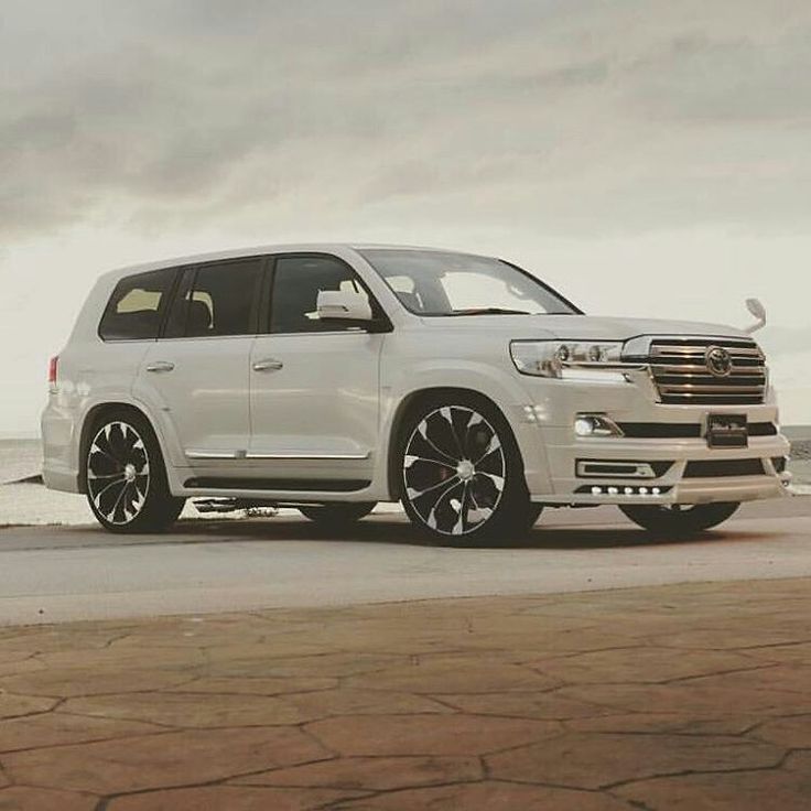 a white suv parked on the side of the road next to the ocean and cloudy sky