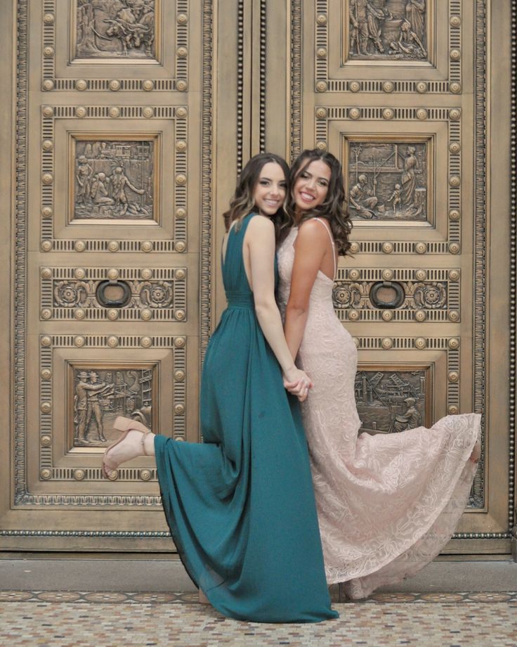 two beautiful women standing next to each other in front of a wooden paneled door