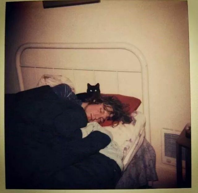 a woman laying in bed next to a black cat