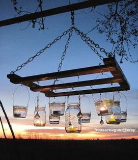 hanging jars filled with water and lit candles are suspended from a beam in the sky