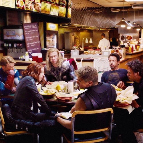 a group of people sitting at a table in a restaurant eating food and talking to each other