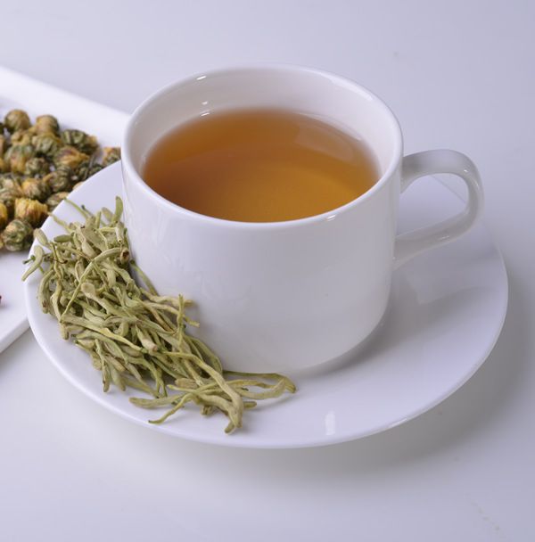 a cup of green tea next to some dried flowers on a saucer and plate