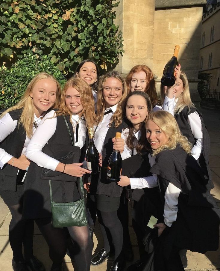 a group of young women standing next to each other holding wine bottles and posing for a photo