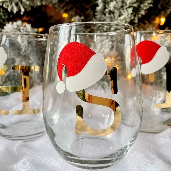 three wine glasses with santa hats on them sitting next to a christmas ornament