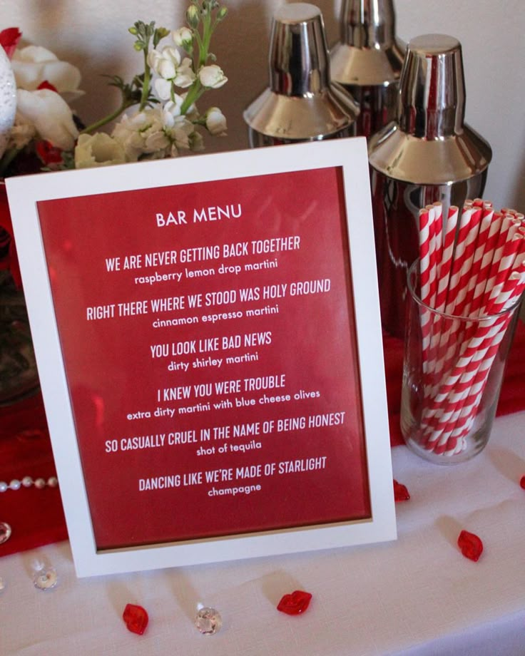 a red sign sitting on top of a table next to silver cups and vases