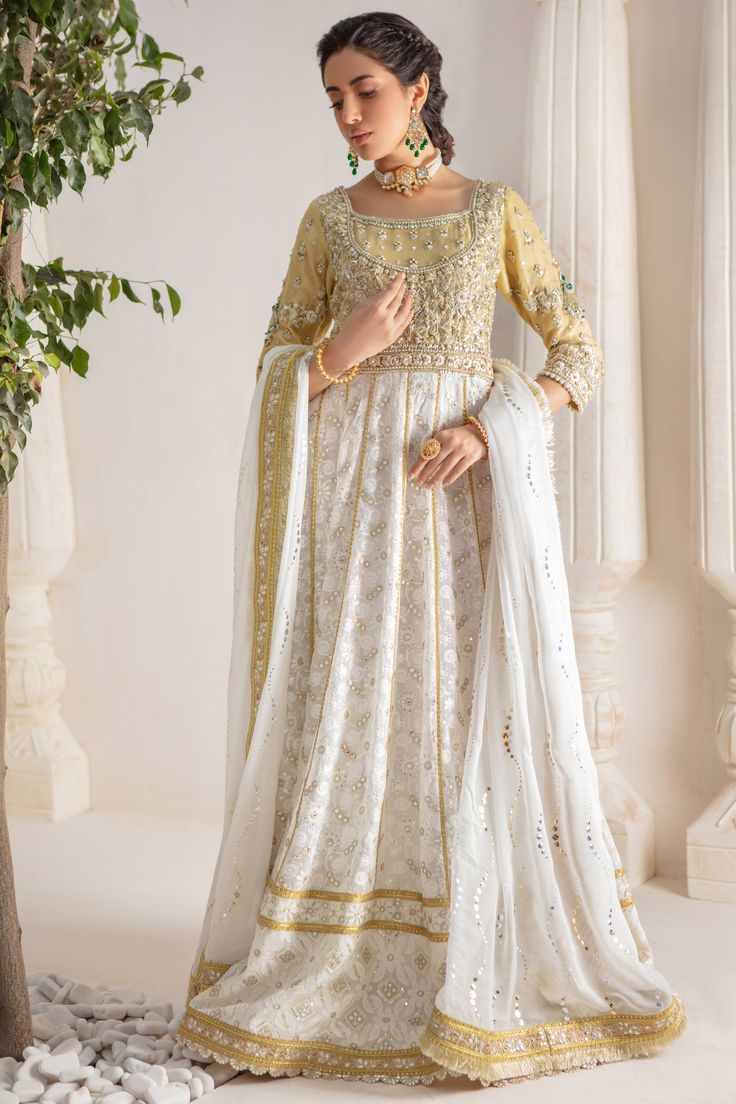 A contemporary Classic - Over a canvas of Pure chikankari chiffon, features a beautiful floral embroidered bodice further enhanced with dabka, sequins, pearls and kundan work. This classy peshwas is paired with gorgeous kamdani work dupatta, making this an absolute favorite for nikkah, engagement & other celebratory festivities Hand crafted tassels & straight pant completes the look of this outfit. Peshwas Fabric: Pure Chiffon Peshwas Length: 60” (customisable, mention in order notes) Sleeve length: 16” Pant Fabric: Khaadi Silk Dupatta Fabric: Georgette Chiffon Color: Ivory & Gold This outfit is fully lined, neck key-hole can be lined on request, mention in order notes. Please refer Size Guide Before selecting size For Customised measurements please select Custom size for an additional 20$ Organza Embroidered Dress With Dabka Work For Reception, White Floor-length Chinon Salwar Kameez, Anarkali Organza Embroidered Dress For Reception, White Embroidered Party Dress, White Maxi Salwar Kameez For Reception, Chiffon Dupatta With Dabka Work For Reception, Dabka Work Dress For Reception, Transitional Georgette Dresses With Resham Embroidery, Wedding Dress With Intricate Embroidery In Georgette