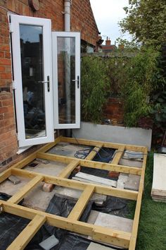 a house being built with wooden boards and windows on the ground in front of it