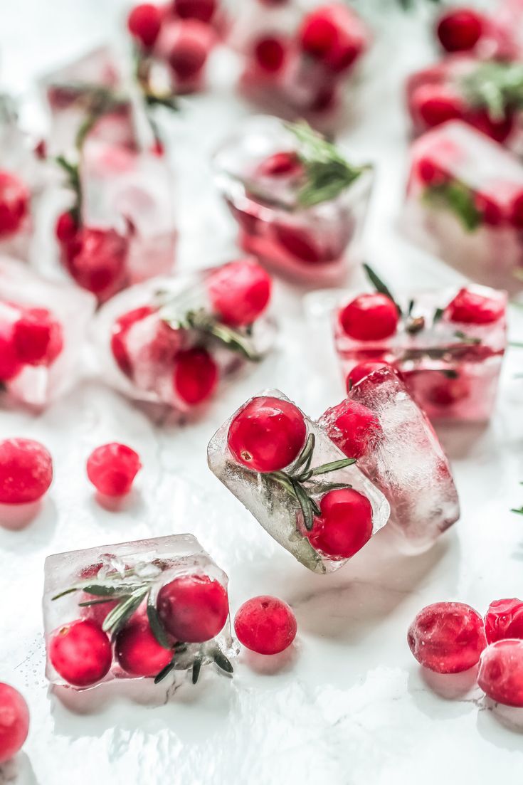 ice cubes filled with cherries on top of a white table covered in water