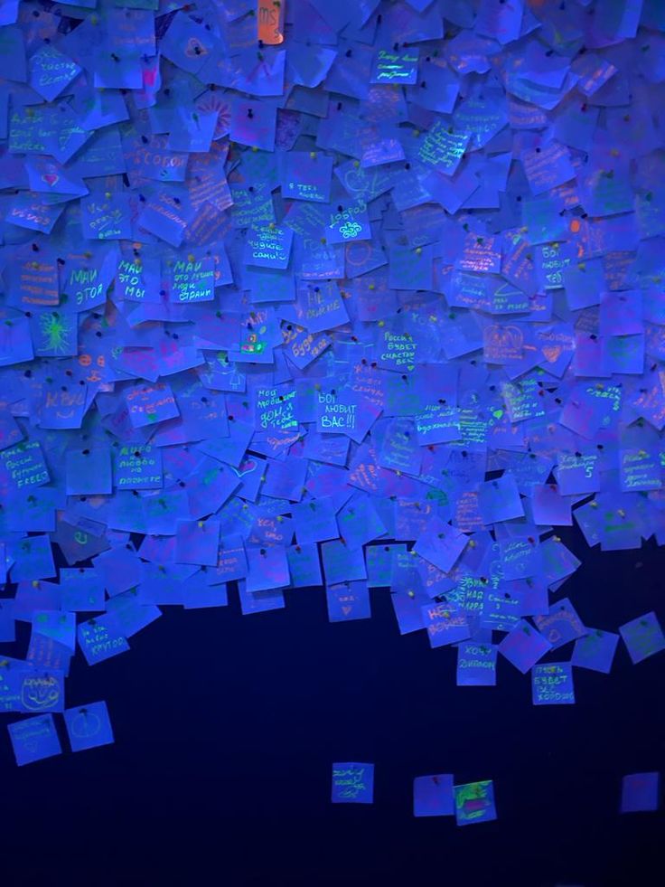 a room filled with lots of blue sticky notes on the wall next to each other