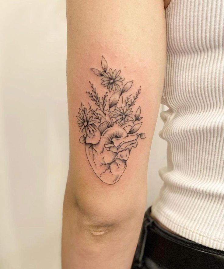 a woman's arm with flowers in the shape of a heart tattoo on it