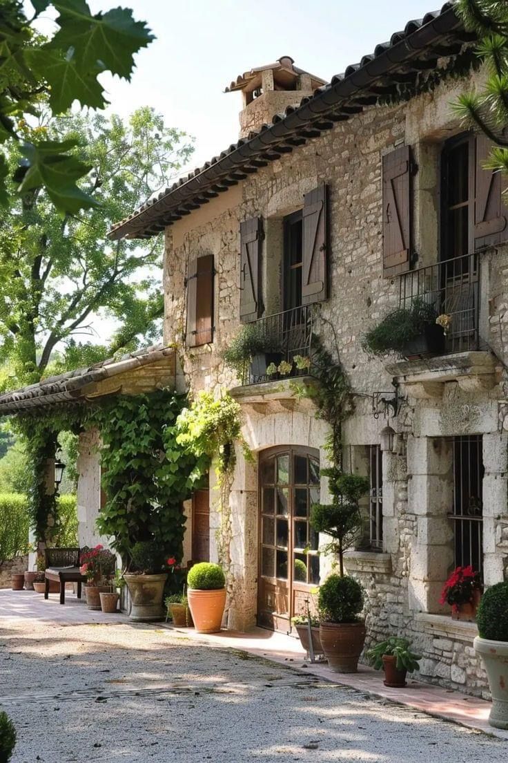 an old stone house with potted plants outside