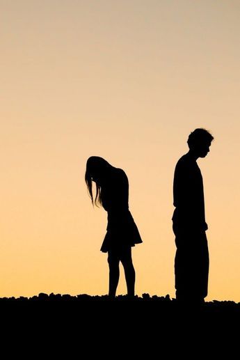 two people are standing in silhouette against an orange sky